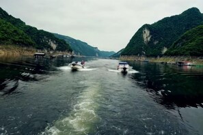 A river with boats, surrounded by green hills. - Guihong Hotel (Zunyi)