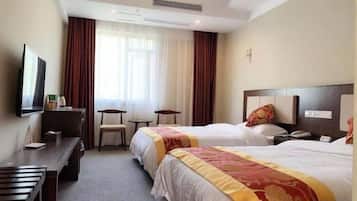 A hotel room with two beds, a desk, a chair, a television, and a window with curtains.