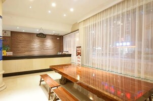 Zona de recepción con mostrador de madera, un banco y un cartel sobre el mostrador.