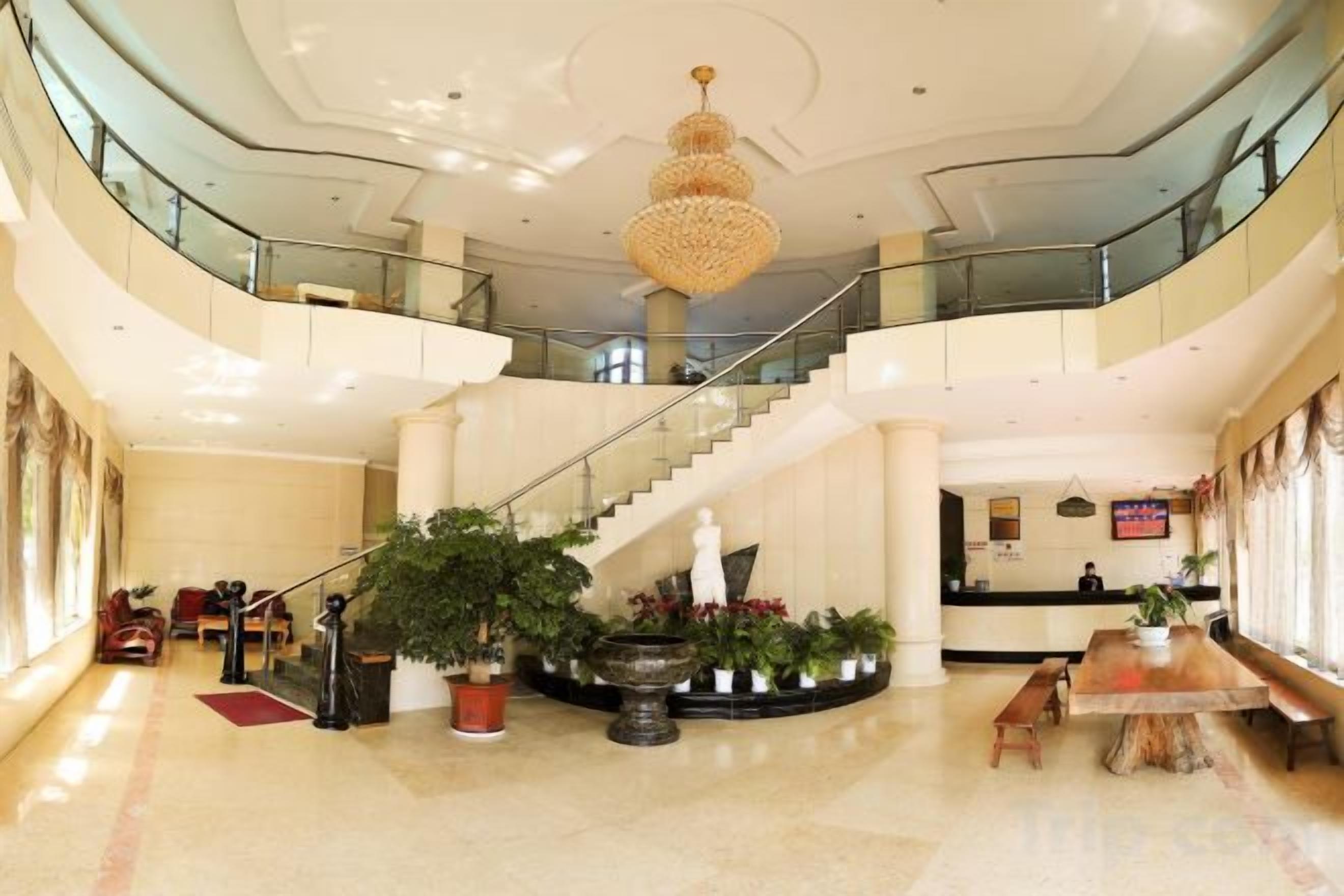 Un hall espacioso con una imponente escalera, una recepción y varias zonas de estar.