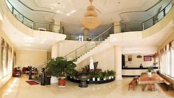 Un hall espacioso con una imponente escalera, una recepción y varias zonas de estar.