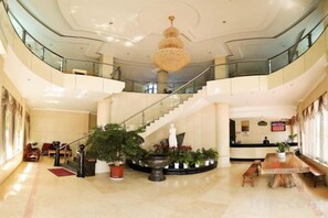 Un hall espacioso con una imponente escalera, una recepción y varias zonas de estar.