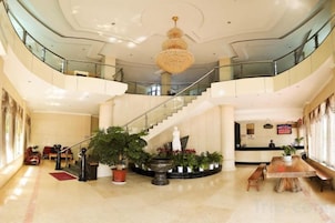 Un hall espacioso con una imponente escalera, una recepción y varias zonas de estar.