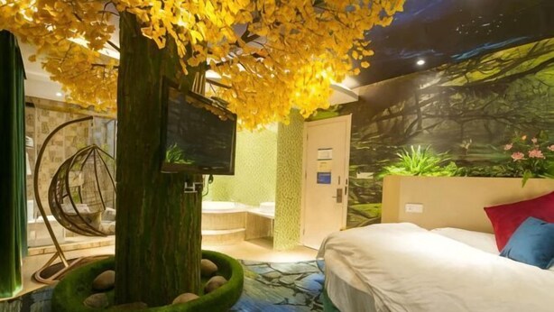 A bedroom with a bed, a television, a hanging chair, and a wall mural. - Yuxi Zhuoran Xinzhuang Hotel (Yuxi)