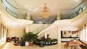 A spacious lobby with a grand staircase, a reception desk, and multiple seating areas. - Yuxi Zhuoran Xinzhuang Hotel (Yuxi)