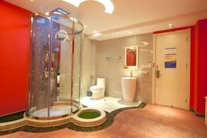 A modern bathroom with a glass-enclosed shower, a large white sink, and a toilet.