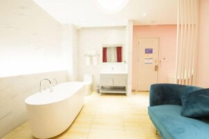 Un baño moderno con una bañera independiente, un tocador con espejo y un sofá azul.