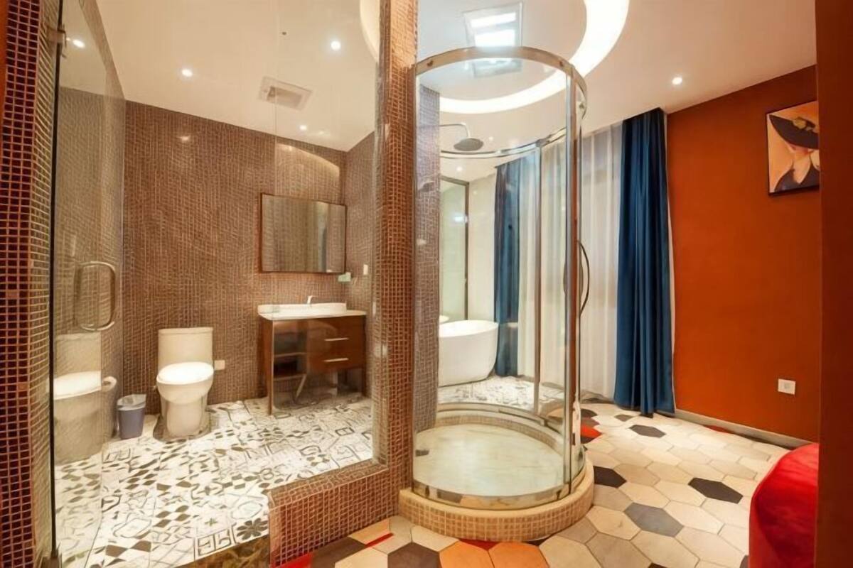 Et moderne badeværelse med en glasafskærmet brusekabine, toilet og vask.