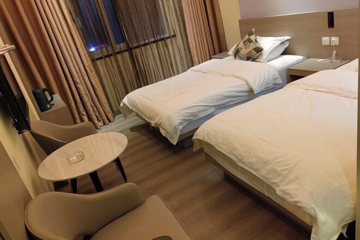 A hotel room with two beds, a small round table, and a chair.