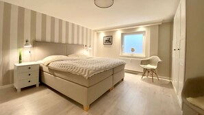 A bedroom with a bed, bedside tables, a chair, a window, and a radiator.