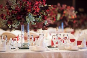 Una mesa dispuesta para un evento formal, con cristalería transparente y manteles blancos.