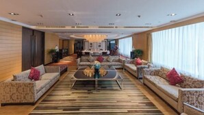Een ruime hotellobby met een centrale salontafel, banken en een kroonluchter.