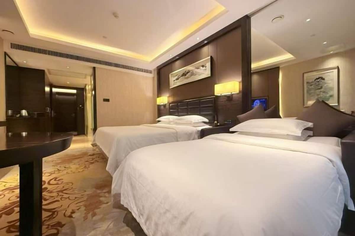 A hotel room with two beds, a desk, and a view of the hallway.