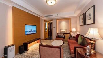 A hotel room with a television, seating area, and a hallway leading to other rooms.