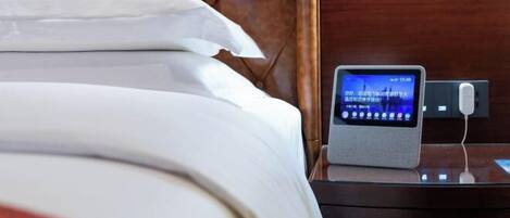 A neatly made bed with white linens, a bedside table with a digital clock, and a wooden headboard.