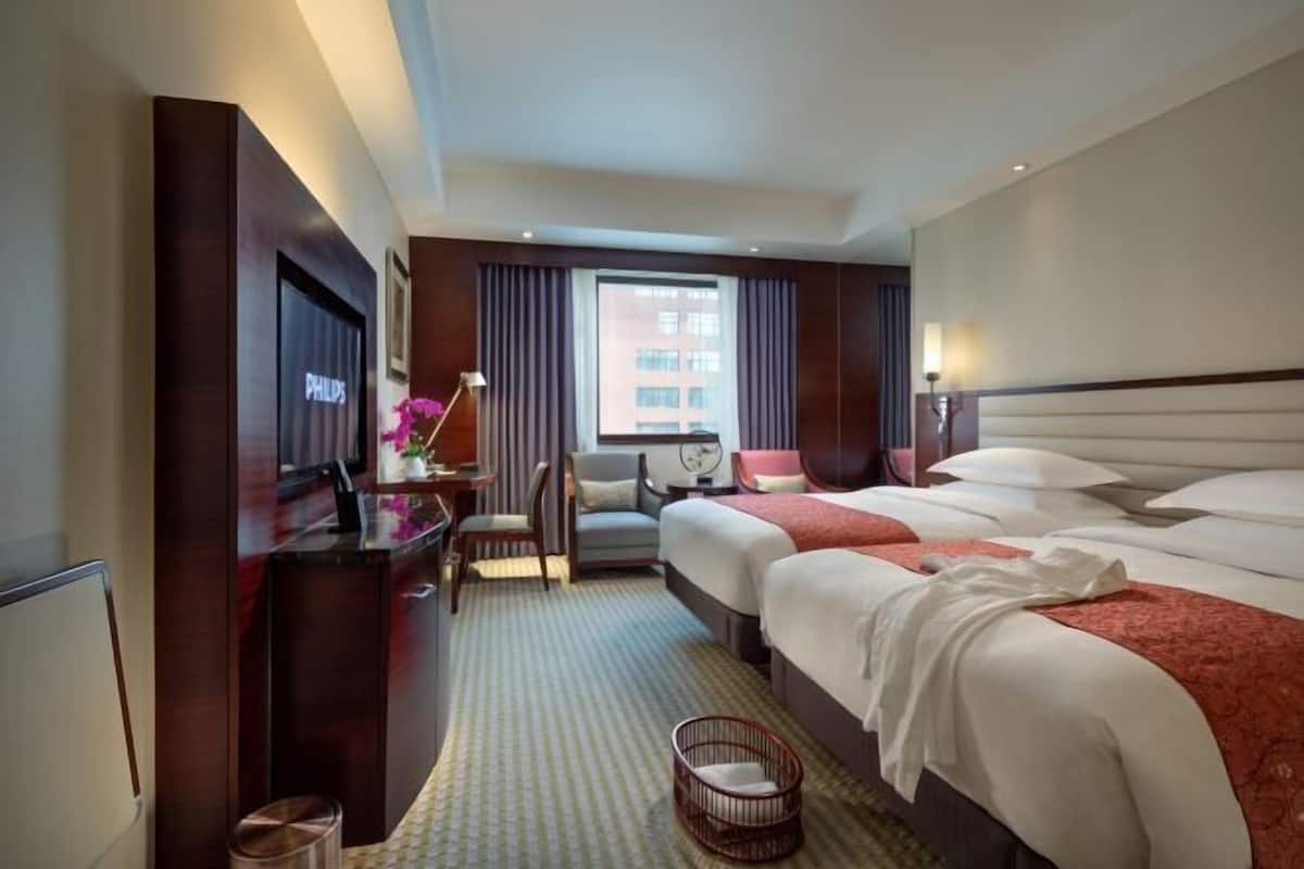 A hotel room with a bed, a desk, a chair, a television, and a window with curtains.