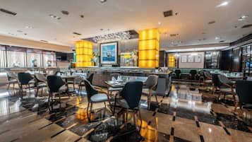 A hotel lobby with a polished marble floor, a reception desk, and seating areas.