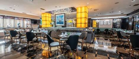 A hotel lobby with a polished marble floor, a reception desk, and seating areas.