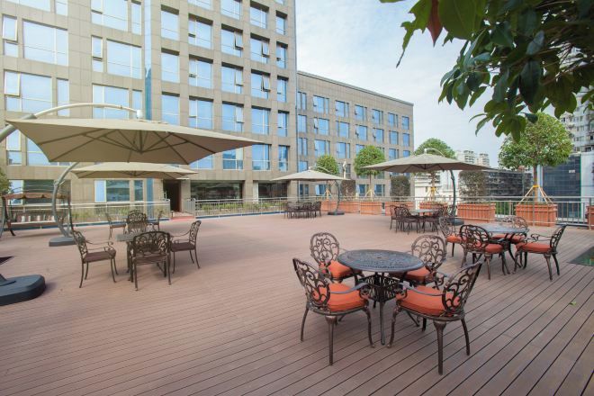 An outdoor patio with tables and chairs, umbrellas, and a building in the background.