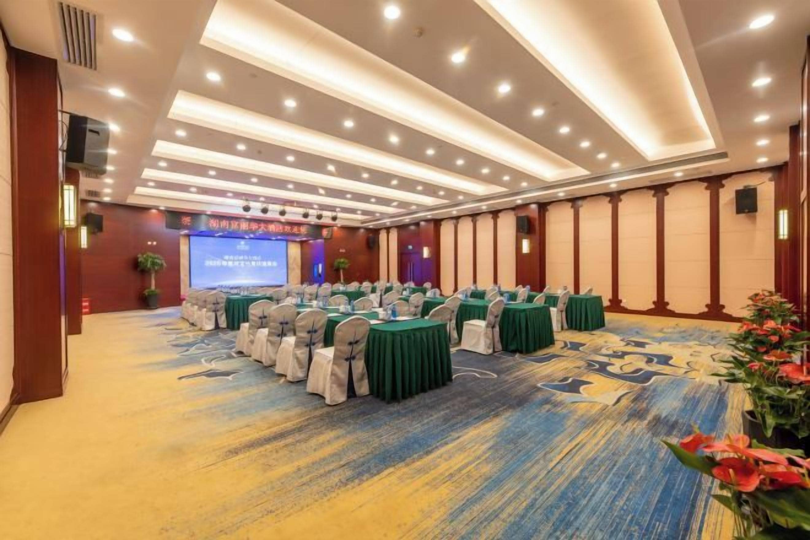 A conference room with rows of tables, chairs, and a projection screen.