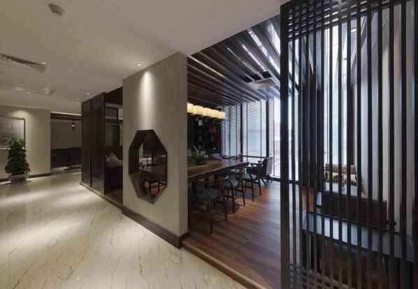 Un intérieur moderne avec un coin repas en bois, une grande fenêtre et un panneau décoratif mural.