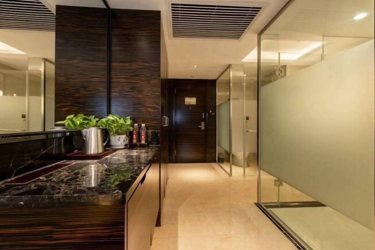 A modern kitchen with a dark wood backsplash, a marble countertop, and a glass door leading to a hallway.