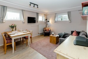 Een gezellige woonkamer met een eethoek, een bank, een salontafel en een televisie.