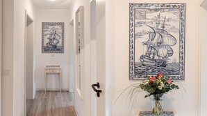 Un couloir doté d’un plancher en bois, d’une petite table et d’un carreau décoratif mural représentant un navire.