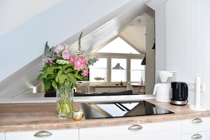A modern kitchen with a wooden countertop, a built-in stove, and a coffee maker.