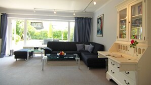 A modern living room with a black sofa, a glass coffee table, and a white cabinet with drawers. - Brise-Sylt - The vacation apartment "Brise-Sylt" is situated at ground level and quietly in (Wenningstedt-Braderup (Sylt))
