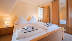 A bedroom with two beds, a nightstand, a lamp, and a wardrobe.