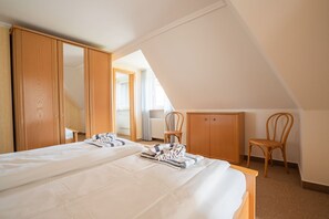 A bedroom with a large bed, wooden wardrobe, and a chair. - Anke im Haus Wega - Relaxed island life: Cozy vacation apartment in (Sylt)