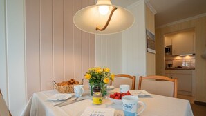 A dining table set with a basket of croissants, a vase of flowers, a bowl of strawberries, and a mug with text.