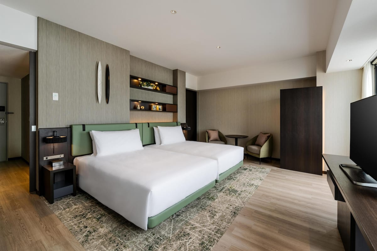 Ein Hotelzimmer mit einem großen Bett, einem Fernseher, einem Schreibtisch und einer kleinen Sitzecke.
