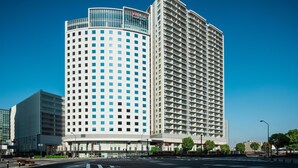 A modern hotel with a curved facade, multiple floors, and a clear sky. - Hilton Garden Inn Yokohama Minatomirai (Yokohama)