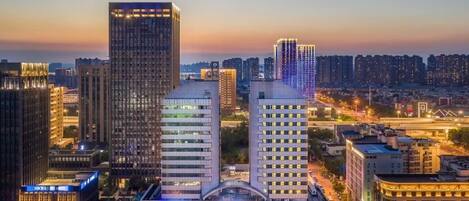 A cityscape with modern high-rise buildings, a prominent hotel with a distinctive dome structure, and a well-lit urban environment.