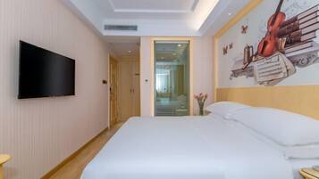 A hotel room with a large bed, a flat-screen TV mounted on the wall, and a mural of musical instruments and books.