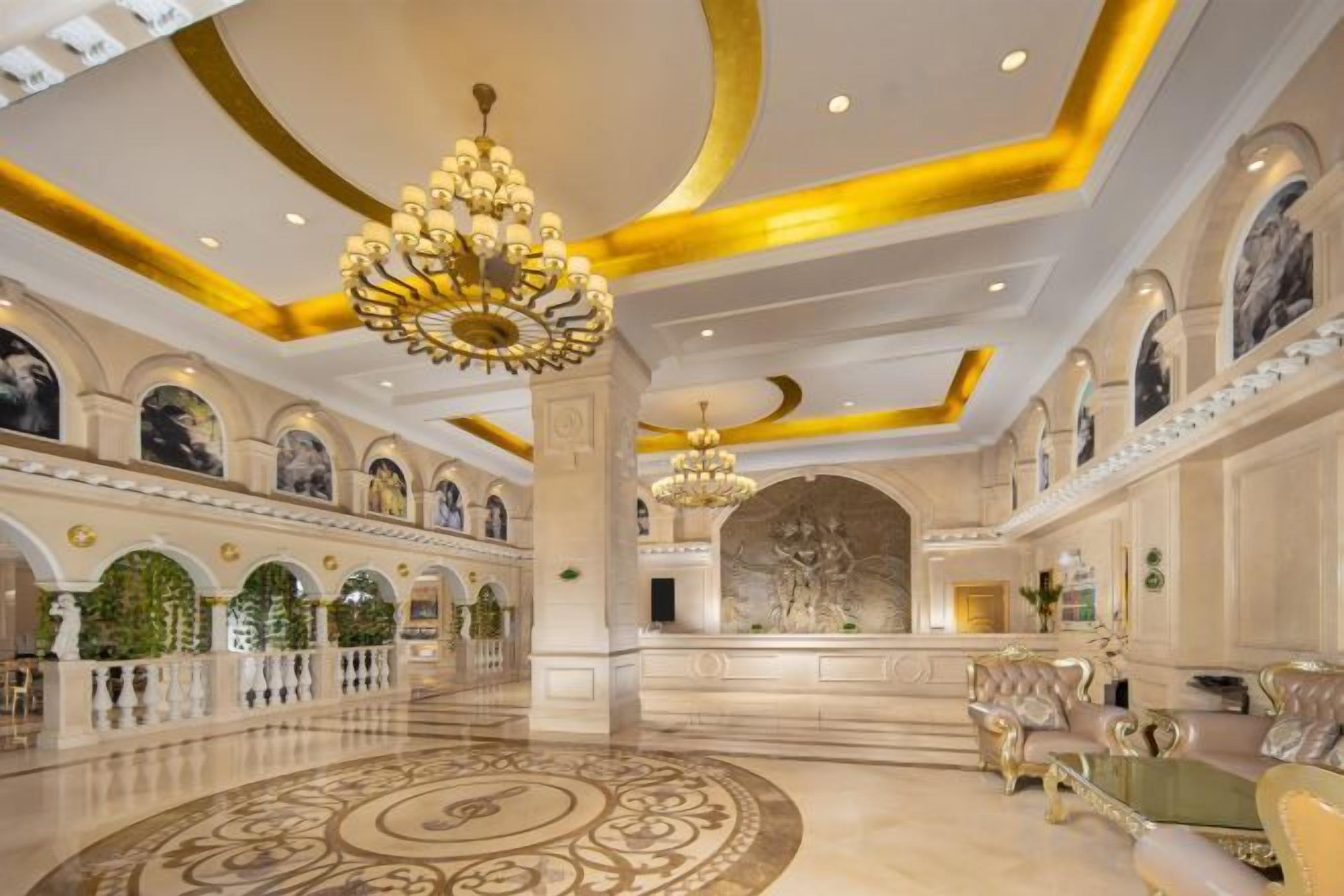 A grand lobby with a large chandelier, ornate columns, and a patterned floor.