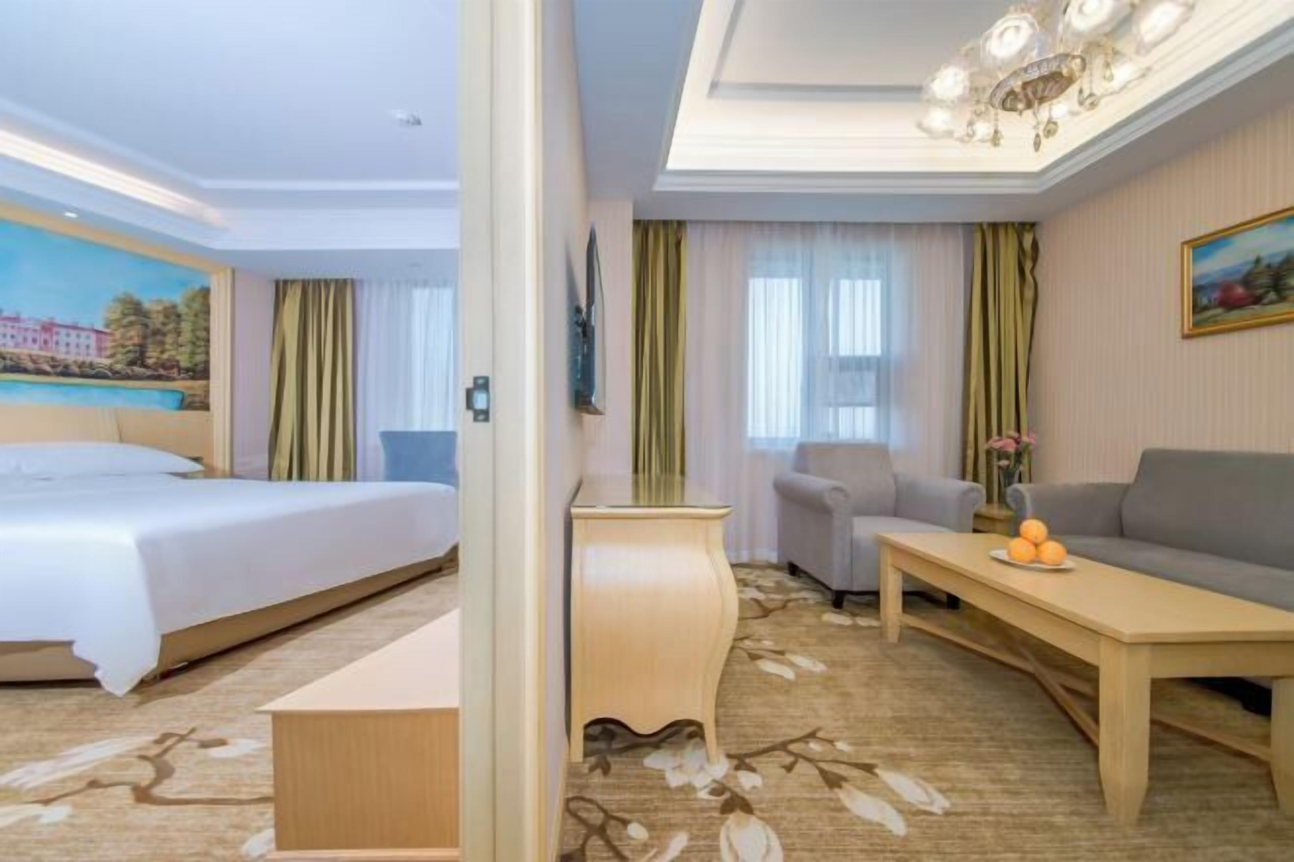 A hotel room with a bed, a desk, a chair, and a sofa.