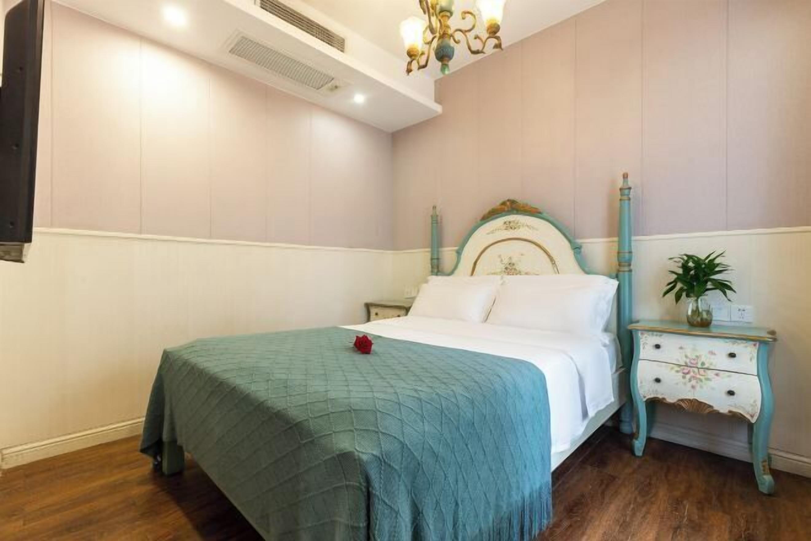 Un dormitorio con una cama, una mesita de noche, un calentador en la pared y una araña.