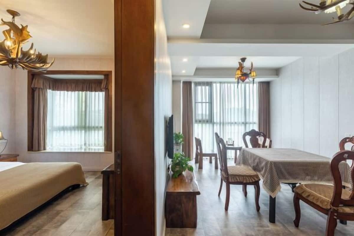 Quarto de hotel com cama, mesa de jantar com cadeiras, um banco de madeira e um candelabro.
