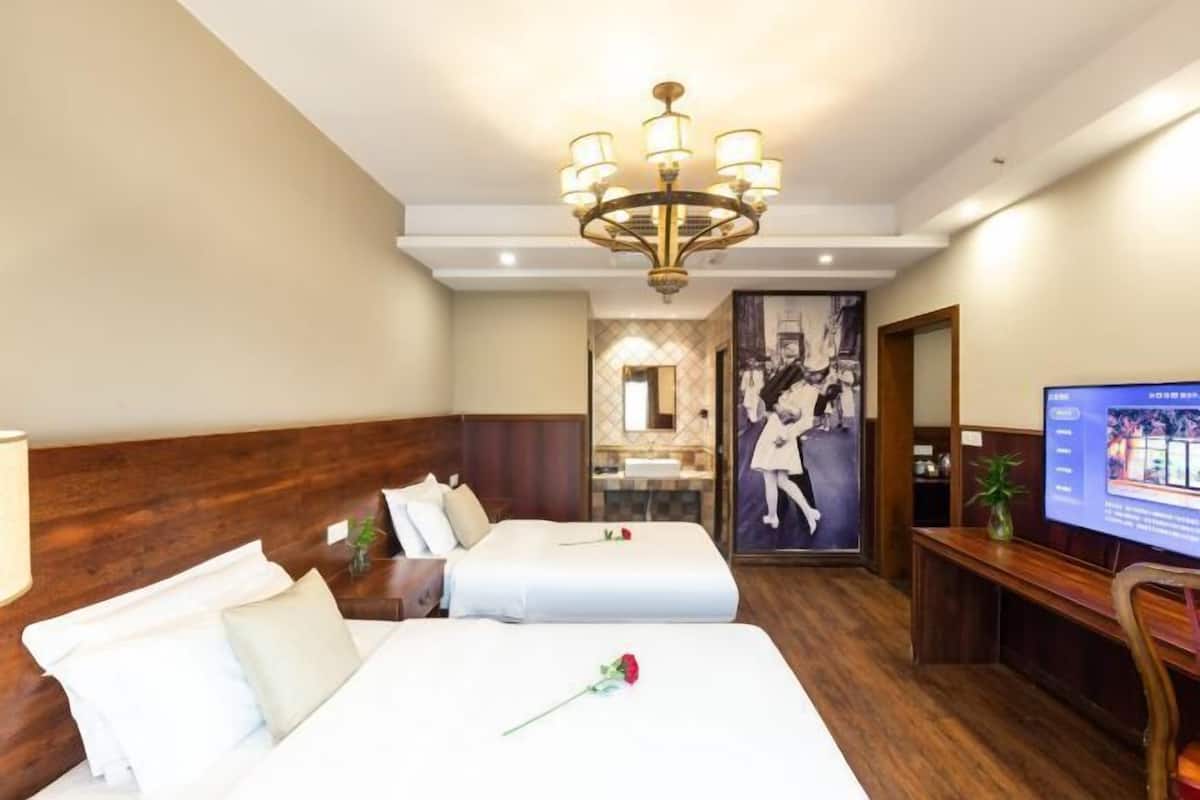 Quarto de hotel com duas camas, um candelabro, uma televisão e um espelho.
