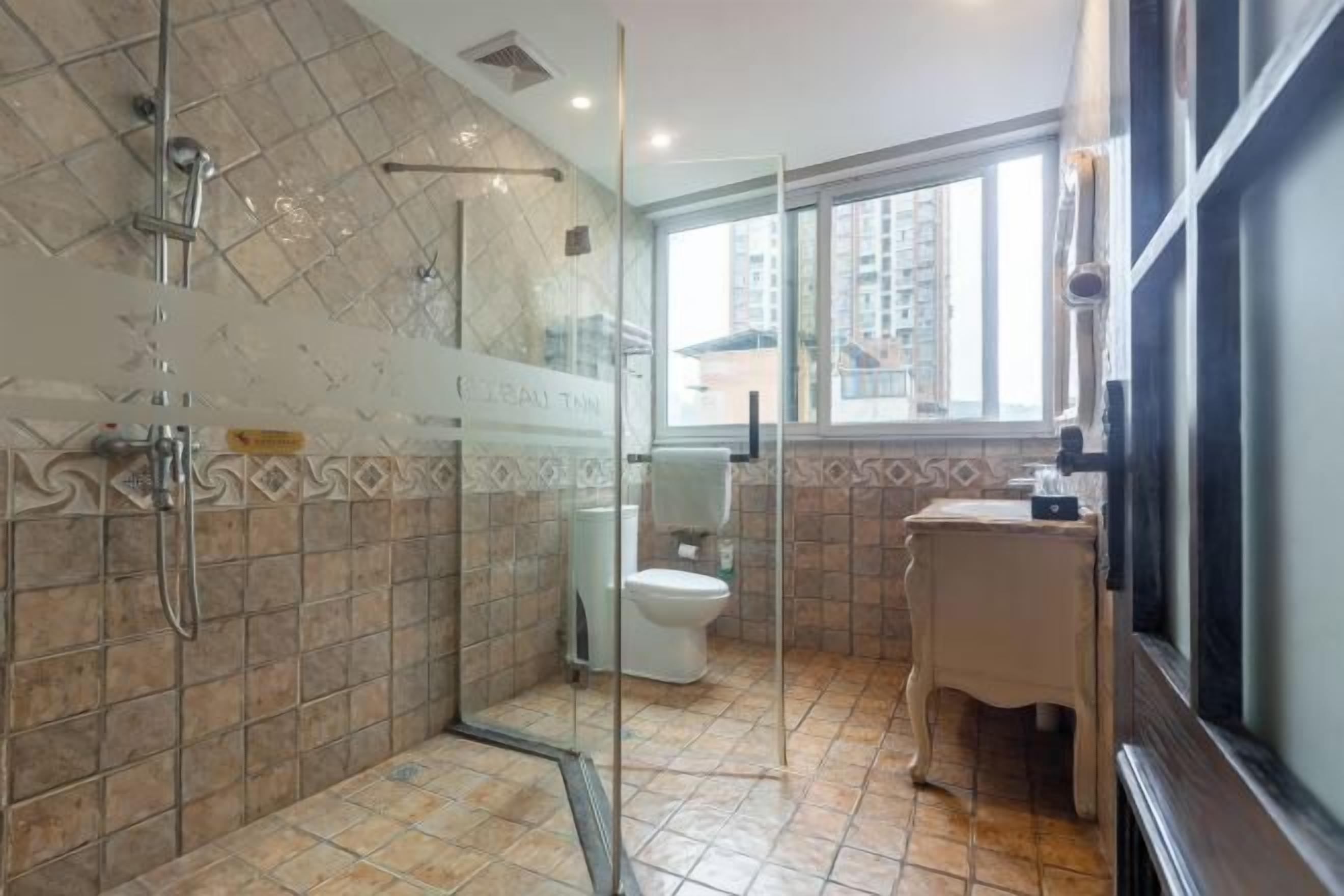 A bathroom with a glass-enclosed shower, a toilet, and a sink.