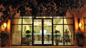 A hotel entrance with glass doors, potted plants, and a brick facade. - Aibao Hotel (Chongqing)