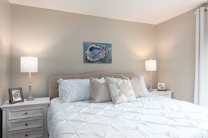 Een slaapkamer met een bed, twee nachtkastjes, een wandlamp en twee lampen.