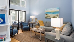 A living room with a sofa, chairs, a coffee table, and a painting of a beach scene.