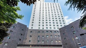A tall, modern building with a symmetrical facade, featuring a central entrance with a red awning and multiple windows. - Liuzhi Gongkuang Hotel (Liupanshui)