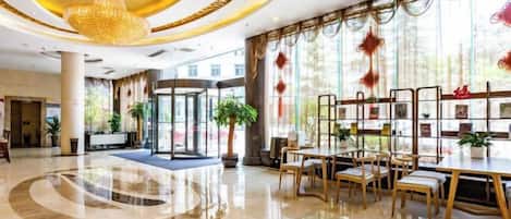 A spacious lobby with a central seating area, a chandelier, and a glass partition with artwork.