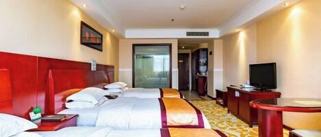 A hotel room with a bed, bedside table, TV, and a desk with a chair.