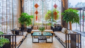 A spacious indoor seating area with sofas, a coffee table, and large windows with curtains. - Liuzhi Gongkuang Hotel (Liupanshui)